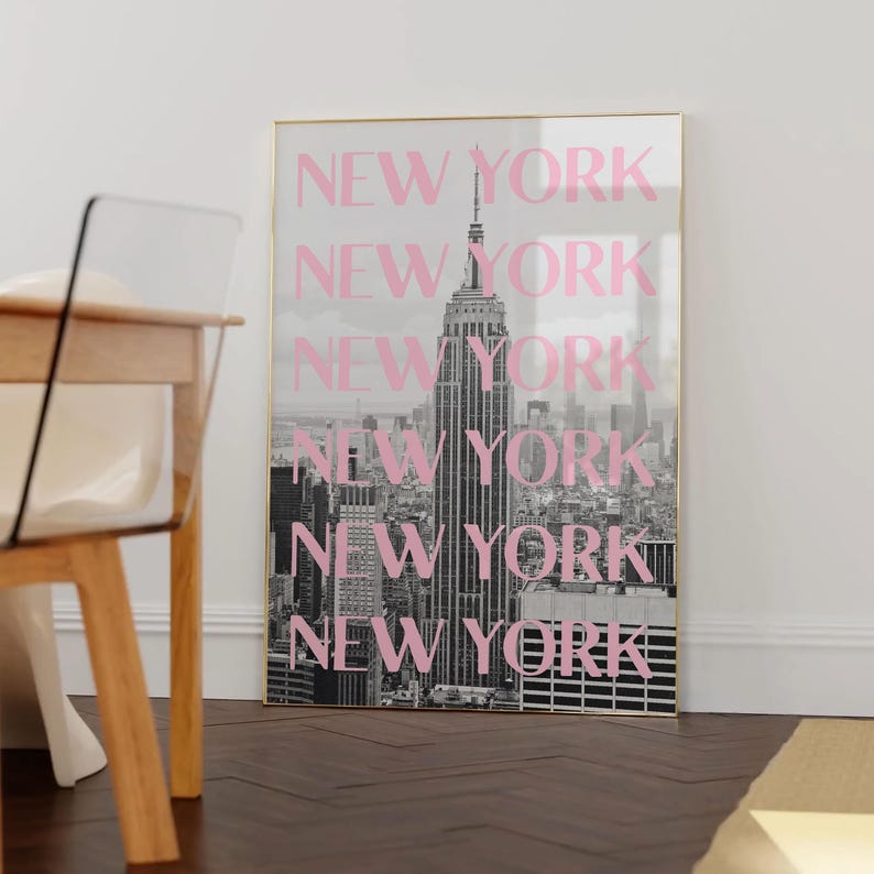 May include: A framed black and white photograph of the New York City skyline, with the Empire State Building prominently featured. The word "NEW YORK" is overlaid in pink, repeated vertically.
