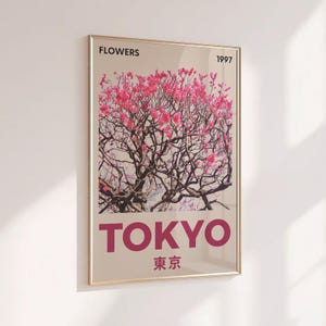 May include: A framed art print featuring a photograph of a flowering tree with pink blossoms. The word "FLOWERS" is at the top, and "TOKYO" is printed in large letters at the bottom, with the year "1997" and Japanese characters below.
