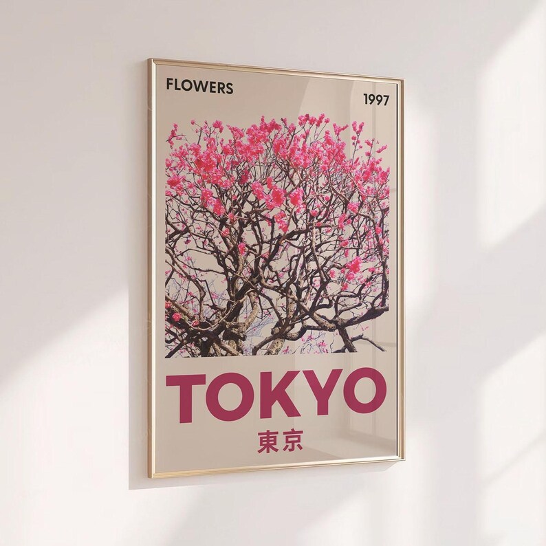 May include: A framed art print featuring a photograph of a flowering tree with pink blossoms. The word "FLOWERS" is at the top, and "TOKYO" is printed in large letters at the bottom, with the year "1997" and Japanese characters below.