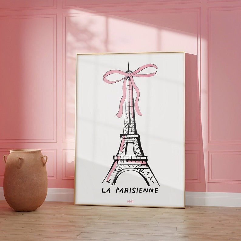 May include: A black and white illustration of the Eiffel Tower with a pink ribbon tied around the top. The text "LA PARISIENNE" is written below the tower.