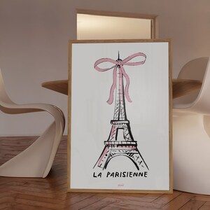 May include: A black and white illustration of the Eiffel Tower with a pink ribbon bow on top. The text "LA PARISIENNE" is below the tower.
