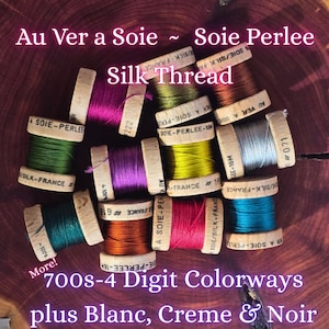 May include: A selection of colourful silk thread spools, with the text "Au Ver a Soie ~ Soie Perlee Silk Thread" and "700s-4 Digit Colorways plus Blanc, Creme & Noir". The spools are in various colours, including green, purple, and orange.