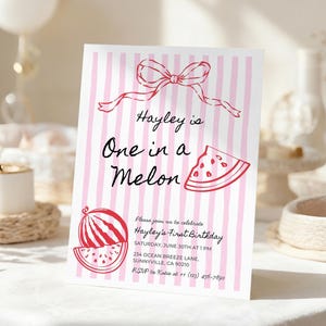 Puede incluir: Una tarjeta de invitación a rayas rosas y blancas con el texto "Hayley is One in a Melon". La tarjeta presenta ilustraciones de sandías y un lazo. La invitación es para el primer cumpleaños de Hayley.