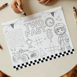 May include: Black and white coloring page with the text "Jackson is Two Fast". The page features a race car, a race car driver, a maze, a trophy, a traffic light, and a checkered flag border.