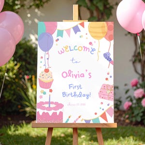 Könnte beinhalten: Ein Willkommensschild für Olivias ersten Geburtstag mit bunten Luftballons, einem Cupcake, einer Torte und dem Text "Welcome to Olivia's First Birthday!" auf einer Holzstaffelei. Rosa Luftballons sind im Hintergrund.
