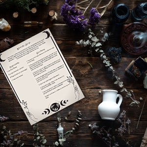 Peut inclure: Une feuille de papier blanche avec du texte noir et des illustrations sur une surface en bois. Le texte indique "Aevender Soup" et énumère les ingrédients et les instructions pour faire une soupe. La surface est entourée de divers objets, notamment des fleurs séchées, de petites bouteilles et un pichet en céramique blanche.