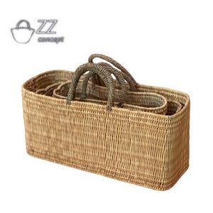May include: A set of three woven baskets with handles. The baskets are made of natural materials and are rectangular in shape. The largest basket is in the foreground and the smallest basket is in the background.