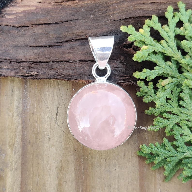 May include: A silver pendant with a round, light pink rose quartz stone.
