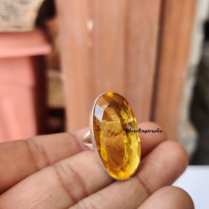 Op de afbeelding: Een zilveren ring met een grote, ovale, gele citrien edelsteen. De ring is gezet in een eenvoudig, elegant ontwerp.
