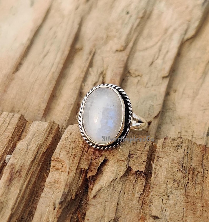 May include: A silver ring with a white oval moonstone set in a twisted silver band.