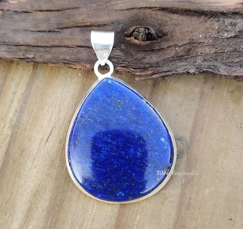 May include: A teardrop-shaped pendant made of silver with a large, deep blue lapis lazuli stone.