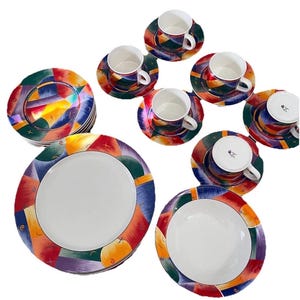 Könnte beinhalten: Ein Set farbenfroher Keramikgeschirr, darunter Teller, Schalen, Untertassen und Teetassen. Die Teller und Untertassen haben ein lebendiges, abstraktes Design mit roten, blauen, grünen und gelben Formen. Die Teetassen und Schalen haben ein weißes Innenleben.