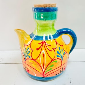 Peut inclure: Un pichet en céramique coloré avec un bouchon en liège. Le pichet est décoré d'un motif floral jaune, orange, rouge, vert et bleu.