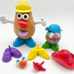 May include: A selection of Mr. Potato Head toy components, featuring a large potato figure with a yellow hard hat, blue shoes, and various accessories such as hats, shoes, and facial features. The toys are brightly coloured and designed for children.