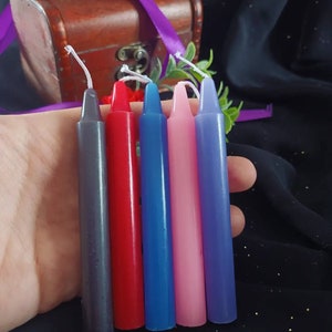 Peut inclure: Cinq bougies de différentes couleurs : gris, rouge, bleu, rose et violet. Les bougies sont toutes de la même taille et de la même forme, et elles sont disposées en rangée.