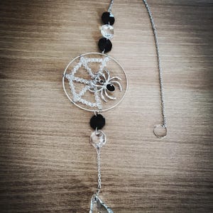 Peut inclure: Décoration suspendue sur le thème d'Halloween, avec un motif de toile d'araignée argentée et une araignée noire au centre. Comprend des perles noires et transparentes, un cristal en forme de goutte et une chaîne argentée.