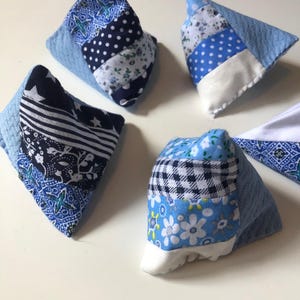 May include: A collection of five pyramid-shaped fabric bean bags featuring various patchwork patterns in shades of blue, white, and black. Each item is constructed from multiple fabric strips with diverse prints including stars, polka dots, and floral motifs.