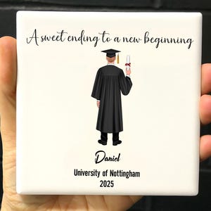 Puede incluir: Una baldosa de cerámica cuadrada con el texto "A sweet ending to a new beginning" y una ilustración de graduación. La ilustración representa a un graduado con toga y birrete negros sosteniendo un diploma. La baldosa también incluye el nombre "Daniel" y "University of Nottingham 2025".