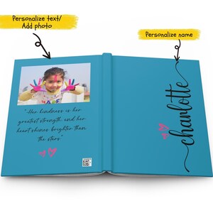 May include: A blue book with a photo of a young girl with colorful paint on her hands. The text "Her kindness is her greatest strength, and her heart shines brighter than the stars" is printed on the left page. The right page has the name "charlotte" written in cursive with two pink hearts.