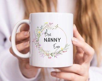 May include: White ceramic mug with a floral wreath design and the text "Best Nanny Ever".