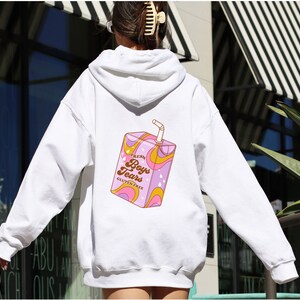 May include: White hoodie with a graphic of a pink and yellow juice box with the text "Fresh Boys Tears Gluten Free" printed on the back.