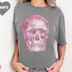 Op de afbeelding: Een grijs T-shirt met een roze glitter schedel print.