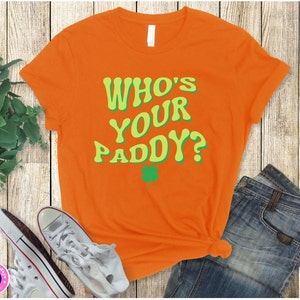 May include: Orange t-shirt with the text "Who's Your Paddy?" in green and yellow letters. A green shamrock is below the text.