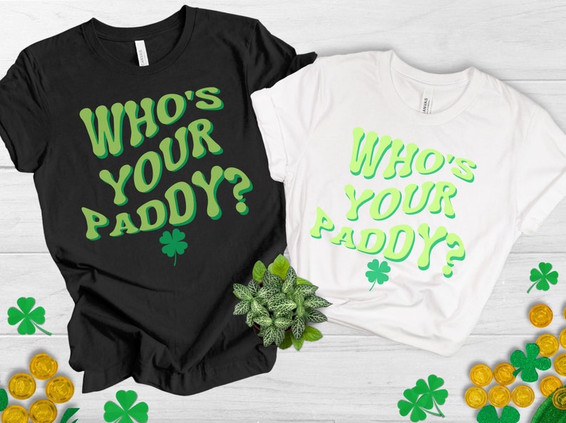 May include: Two t-shirts with the text "Who's Your Paddy?" in a green and white retro font. The shirts are black and white and have a shamrock design.