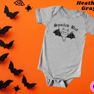 May include: A heather gray baby onesie with a black and white illustration of a bat with the text "Spoiled Bat" in a gothic font.