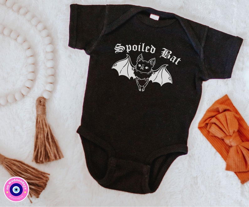 May include: Black baby onesie with a white graphic of a bat with the text "Spoiled Bat" in a gothic font.