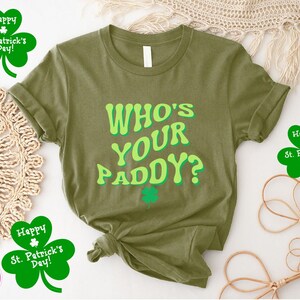 May include: A green t-shirt with the text "WHO'S YOUR PADDY?" in a retro font. The shirt is surrounded by shamrocks with the text "Happy St. Patrick's Day!"