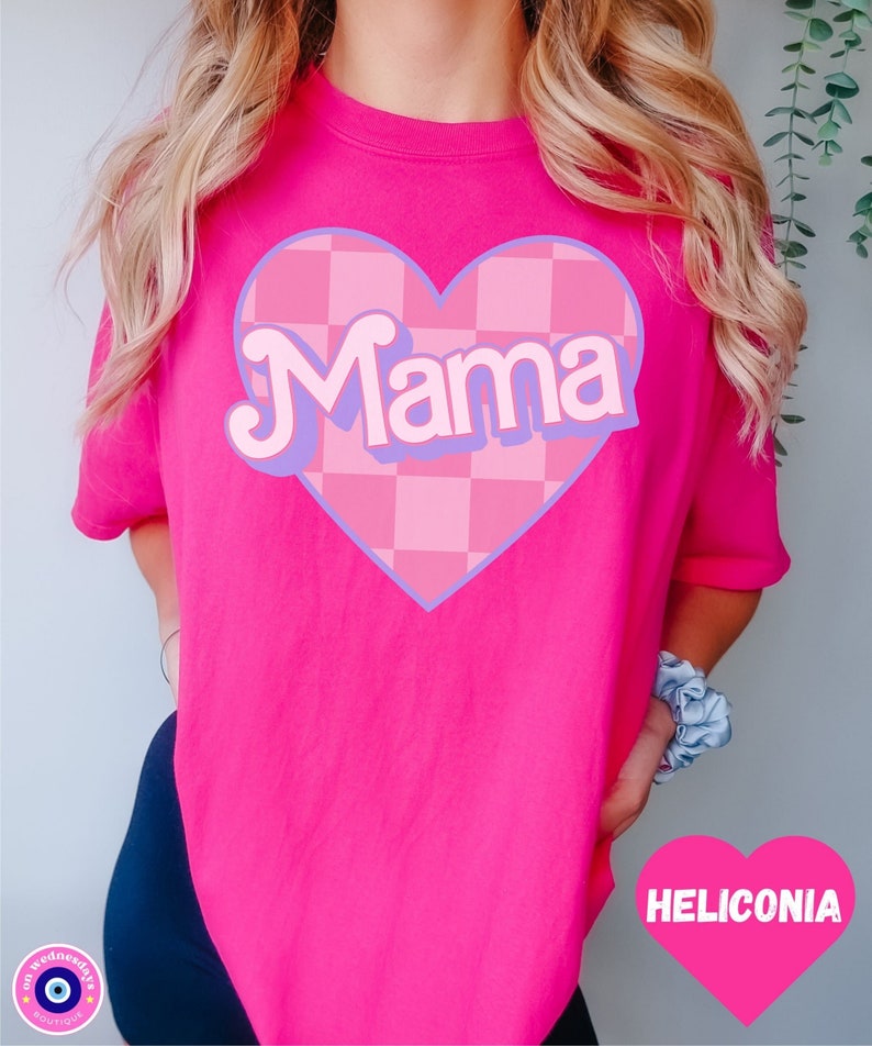 Puede incluir: Camiseta rosa con un gran gr&aacute;fico de coraz&oacute;n rosa y morado que dice "Mama" en una fuente retro. El coraz&oacute;n tiene un patr&oacute;n a cuadros.