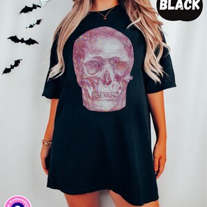 Op de afbeelding: Zwart oversized T-shirt met een glinsterende roze en witte schedelprint. De schedel heeft een gedetailleerd ontwerp met zichtbare tanden en oogkassen.