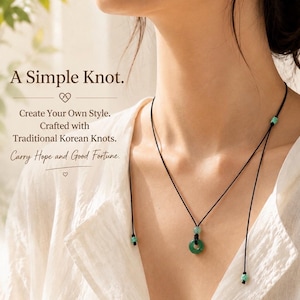 May include: A necklace featuring a green circular stone pendant on a thin black cord. The cord includes small turquoise-colored beads and is tied with knots. Text on the image reads: A Simple Knot. Create Your Own Style. Crafted with Traditional Korean Knots. Carry Hope and Good Fortune.