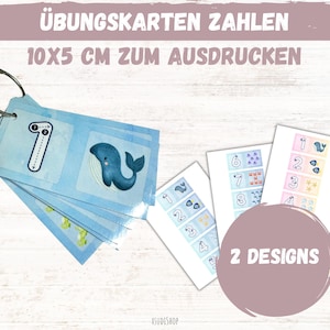 Op de afbeelding: Educatieve flashcards voor het leren van getallen, 10x5 cm, met een blauwe walvis illustratie en het nummer 1. De kaarten zijn bevestigd met een metalen ring. De tekst "2 DESIGNS" is zichtbaar.
