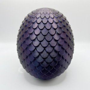 May include: A dark purple dragon egg with a textured, scaly surface. The egg is a decorative object and is made of a hard material.
