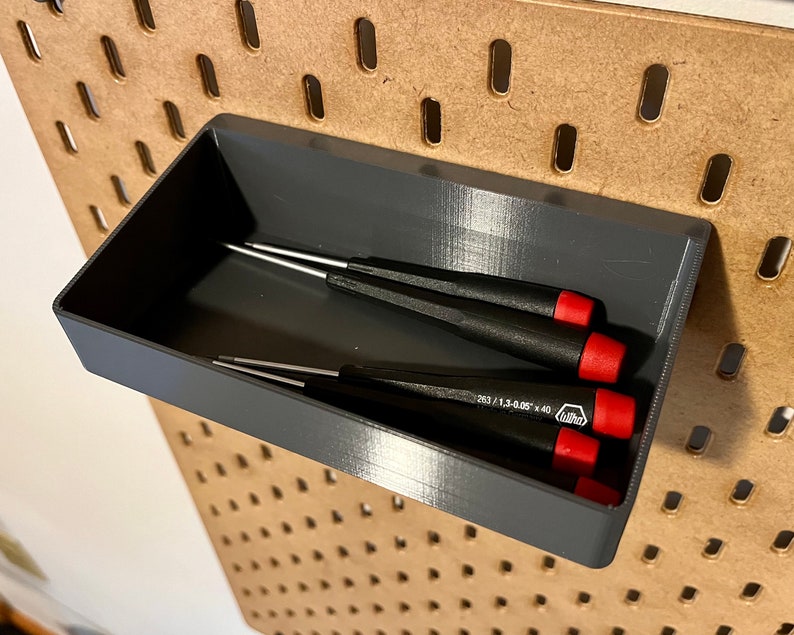 May include: A gray plastic tool organizer with four screwdrivers inside. The organizer is mounted on a pegboard wall.