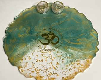 May include: A round, green and gold resin tray with a gold Om symbol and Sanskrit text. The tray has two small gold cups on top.