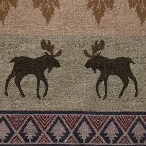 May include: Textile with a repeating pattern featuring two dark brown moose silhouettes. The design includes a border with geometric shapes in shades of red, blue, and gray, and leaf-like motifs at the top. The background is a textured, neutral color.