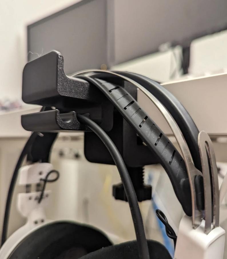 Puede incluir: Soporte negro para auriculares con auriculares y cable negros. El soporte est&aacute; montado en un estante blanco. Los auriculares tienen auriculares blancos y una diadema negra. El soporte est&aacute; dise&ntilde;ado para sujetar los auriculares.
