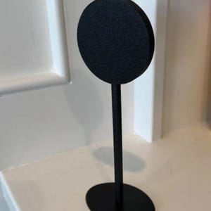 May include: A black metal display stand with a round top and an oval base.
