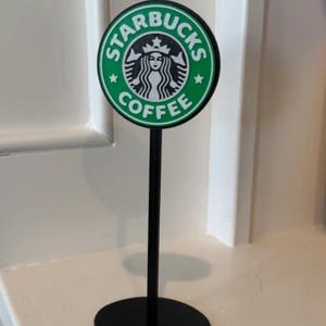 以下が含まれることがあります： 「スターバックスコーヒー」と書かれた緑と白のスターバックスロゴが付いた黒いスタンドです。