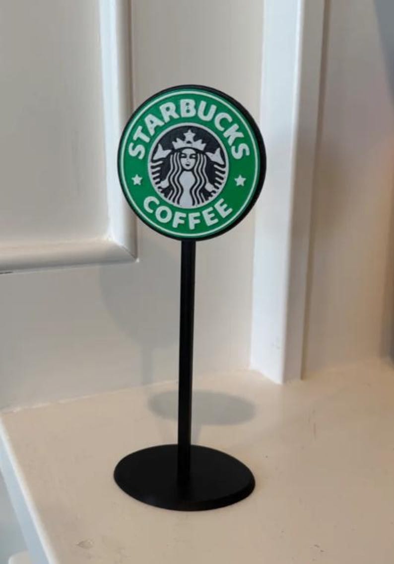 May include: A black stand with a green and white Starbucks logo that says "Starbucks Coffee".