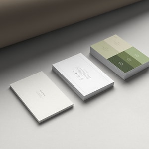 Pode incluir: Um monte de cart&otilde;es de visita brancos com um ponto preto e texto, e um monte de cart&otilde;es de visita verdes e brancos com texto.