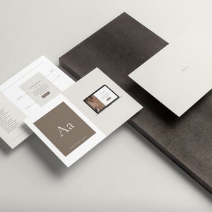 Pode incluir: Uma maquete de um pacote de marca com um fundo branco. O pacote inclui um folheto, um cart&atilde;o de visita, uma tela de laptop e um cart&atilde;o de tipografia. O folheto tem um fundo cinza com o texto "The Brand Guide" e um bot&atilde;o que diz "Learn More". O cart&atilde;o de visita &eacute; branco com o texto "Company Name". A tela do laptop mostra um site com uma foto de uma mulher. O cart&atilde;o de tipografia &eacute; marrom com o texto "Aa" em uma fonte branca.