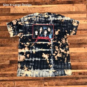 May include: Black and white tie-dye t-shirt with a red framed image of the band Metallica. The band members are wearing black clothing and are standing in front of a dark background. The t-shirt is a size X-Large.