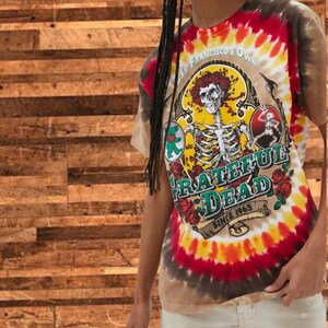May include: Tie-dye t-shirt with a Grateful Dead logo featuring a skeleton with a flower crown, a bear, and the text "San Francisco's Own Grateful Dead Since 1965".