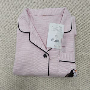 May include: Pink and white striped pajama set with black trim and a penguin embroidery. The set includes a collared shirt with a button closure and a pocket. The tag reads ETCOZY.