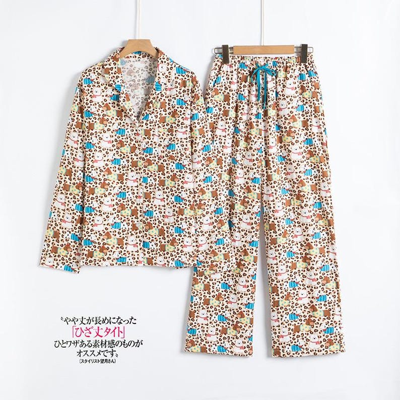 May include: A two-piece pajama set with a white background and a repeating pattern of brown, blue, and tan animal and floral shapes. The top is a button-down shirt, and the pants have a drawstring waist. The Japanese text is visible.