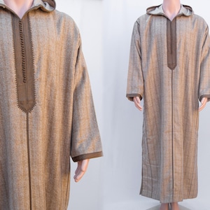 Op de afbeelding: Een lange, bruine gekapte robe met een bruin geborduurd ontwerp aan de voorkant. De robe heeft een lange, vloeiende silhouet en is gemaakt van een zachte, gestructureerde stof.
